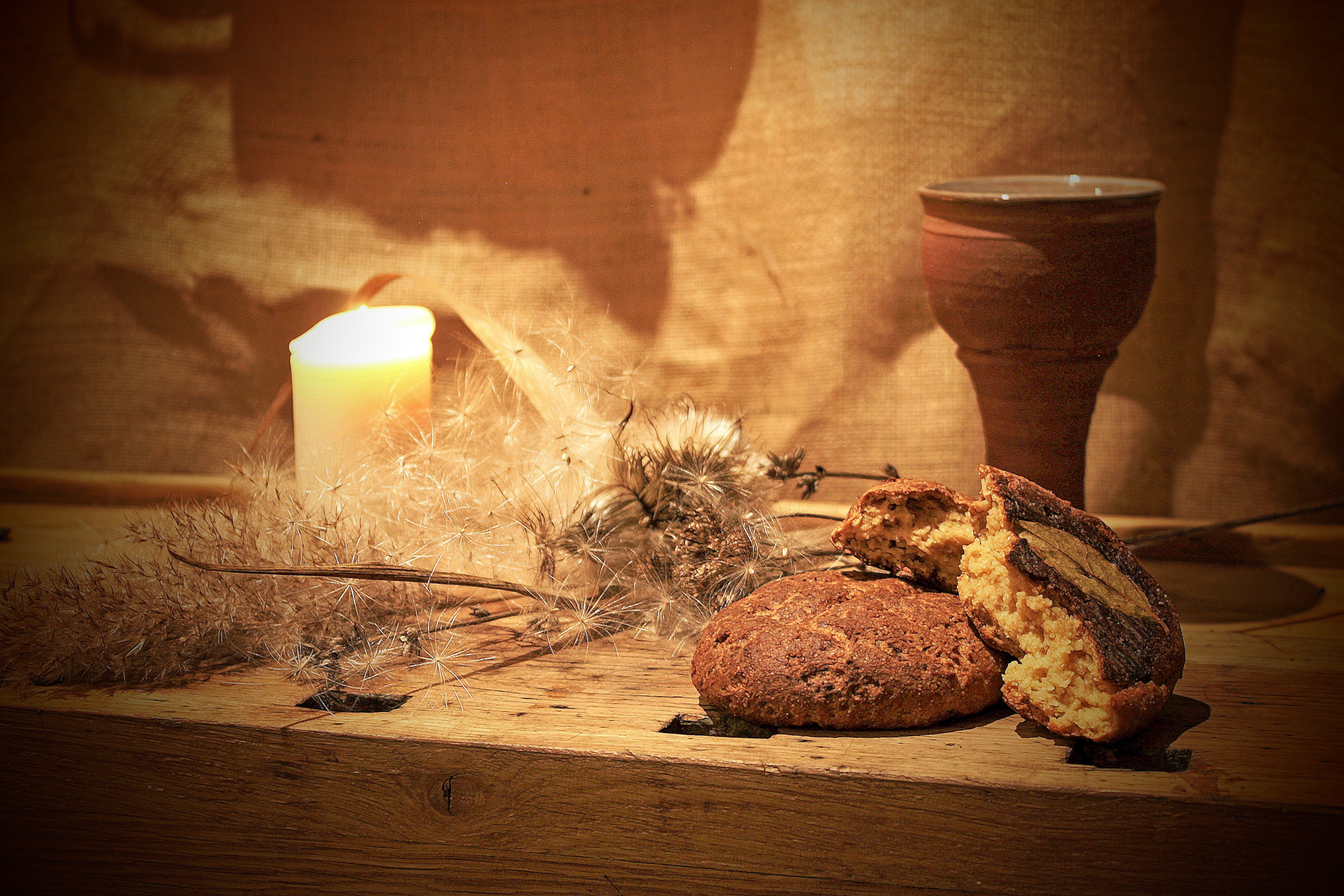 A still life of bread, a candle, and a clay cup staged as part of the Food-Art Collective's food memory and publication work.