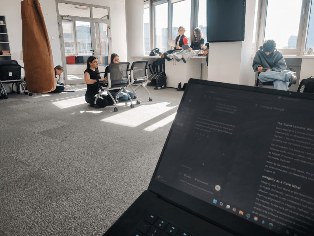 The Dojo studio in session, with students working quietly across the room while reflective writing is open on a laptop in the foreground.