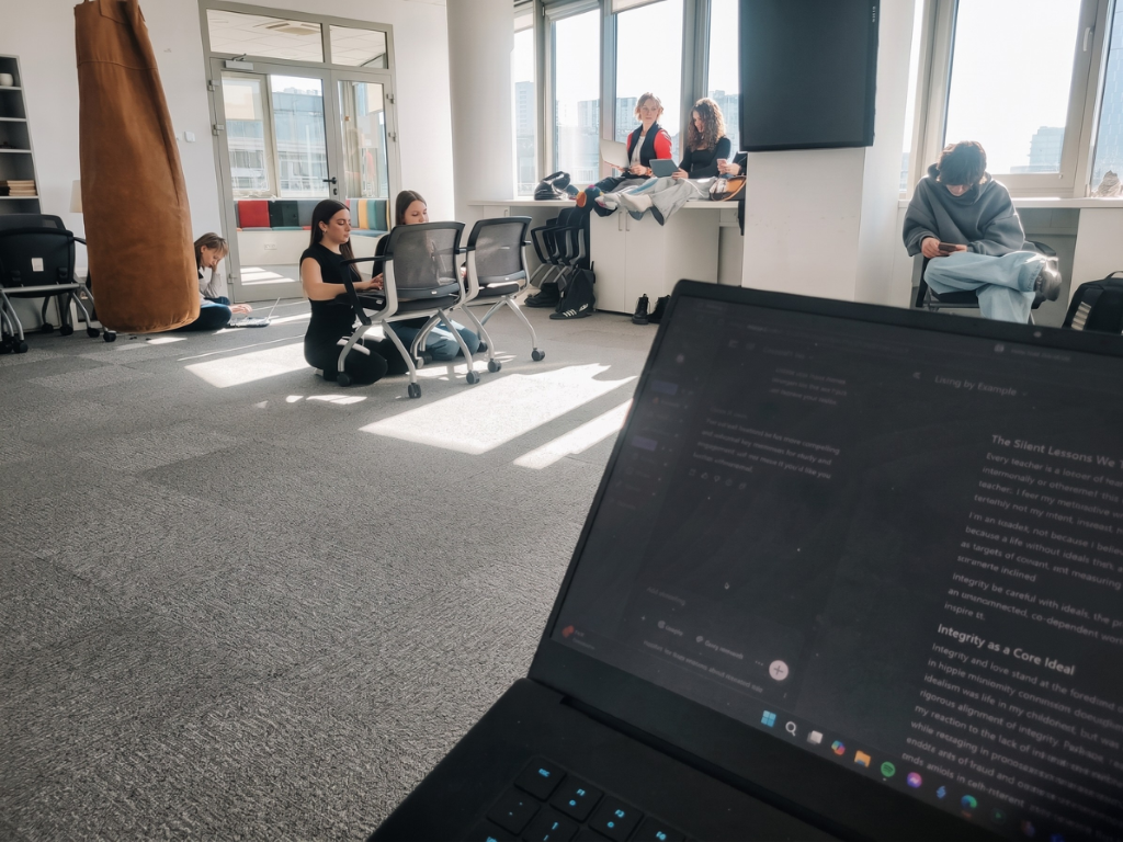 The Dojo studio in session, with students working quietly across the room while reflective writing is open on a laptop in the foreground.