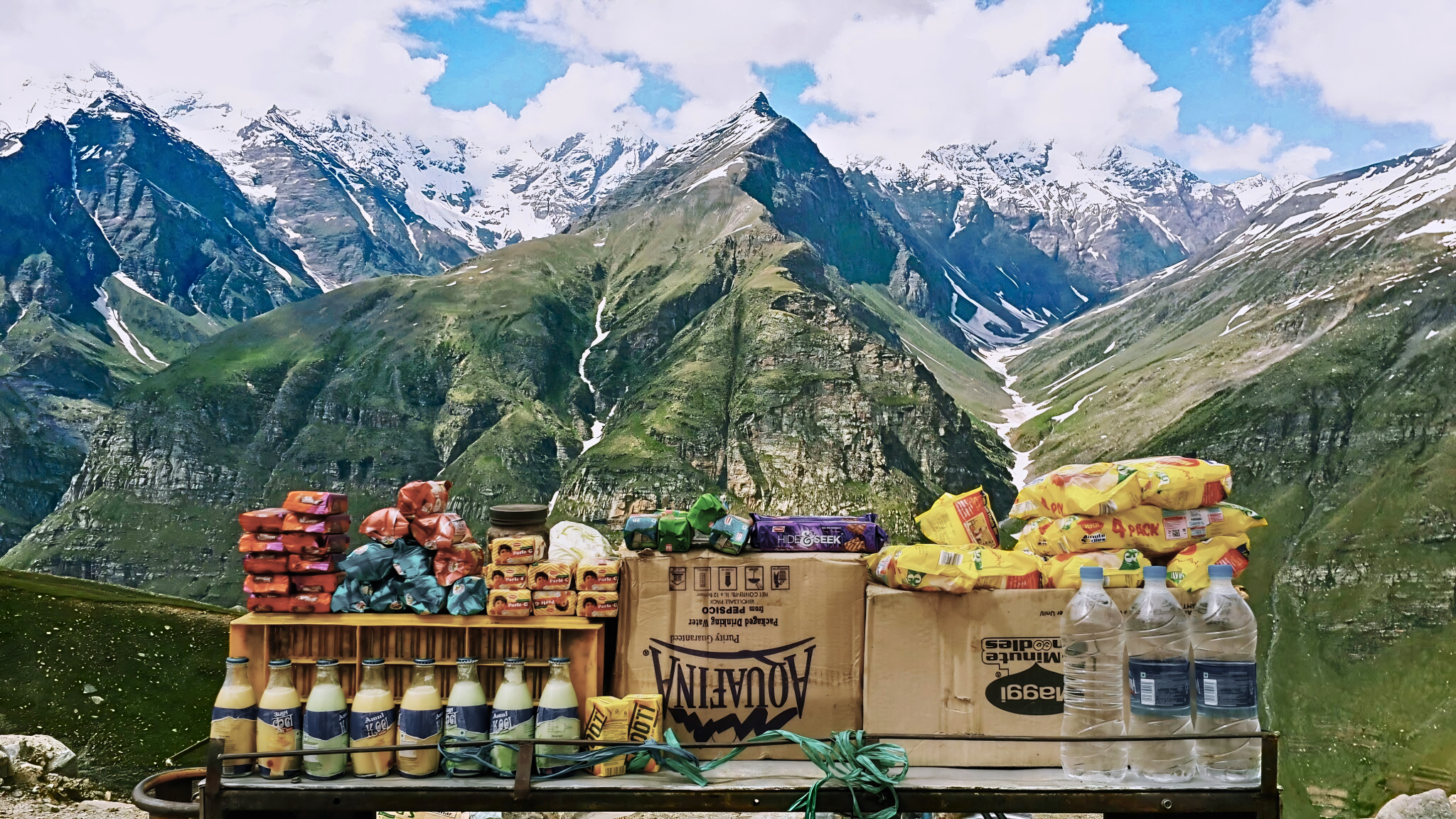 Food supplies arranged in front of a high mountain landscape.